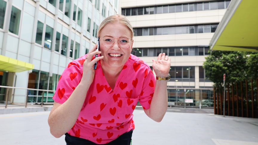A woman in pink scrubs speaks on a cell phone at PA Hospital, engaged in conversation