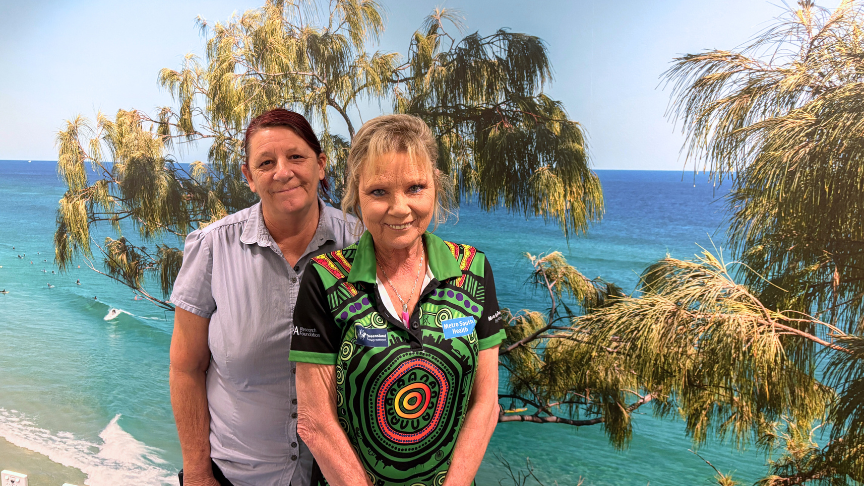 Two mental health nurses in front of large artwork smiling