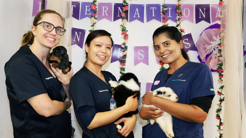 three female nurses holding puppies in front of IND signage