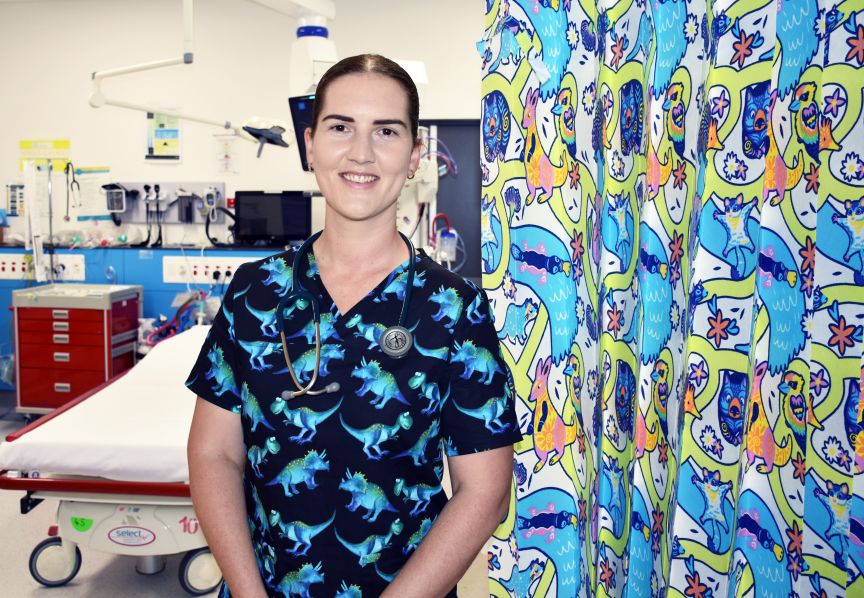 Headshot of female nurse wearing dinosaur scrub top