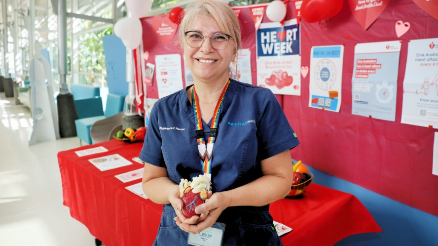Mary Weglowski, in blue scrubs, proudly holds a model heart while celebrating her 40 years at PA Hospital