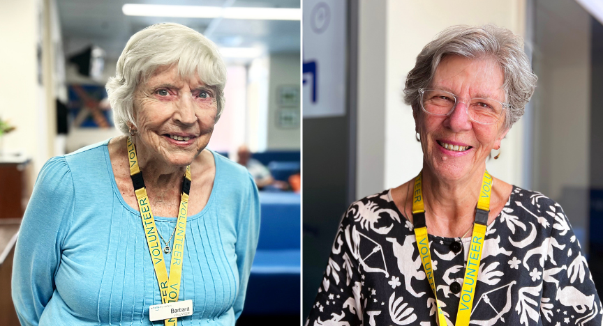 Two older women, Barbara and Margaret, smiling and wearing yellow lanyards, serve as dedicated volunteers at PA Hospital
