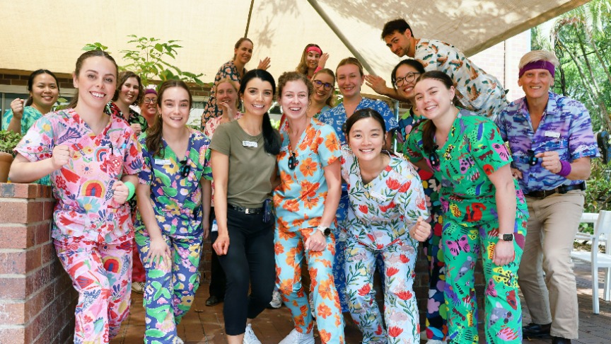 OTs gathered in courtyard in frozen running positions and colourful scrubs on