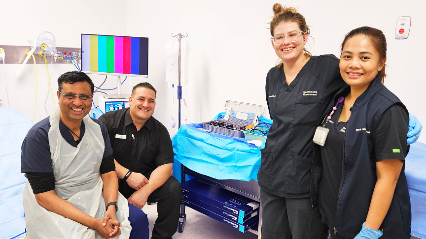 Four healthcare professionals sitting and standing together in a clinical space