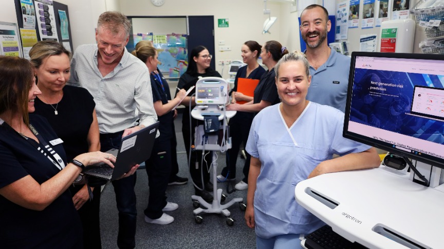 A group of hospital staff gathered around a computer, discussing the Atidia patient optimiser program