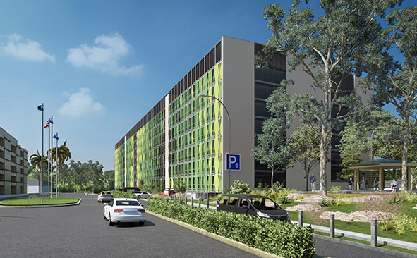 Modern building with a green facade, parking area, and gardens under a cloudy sky
