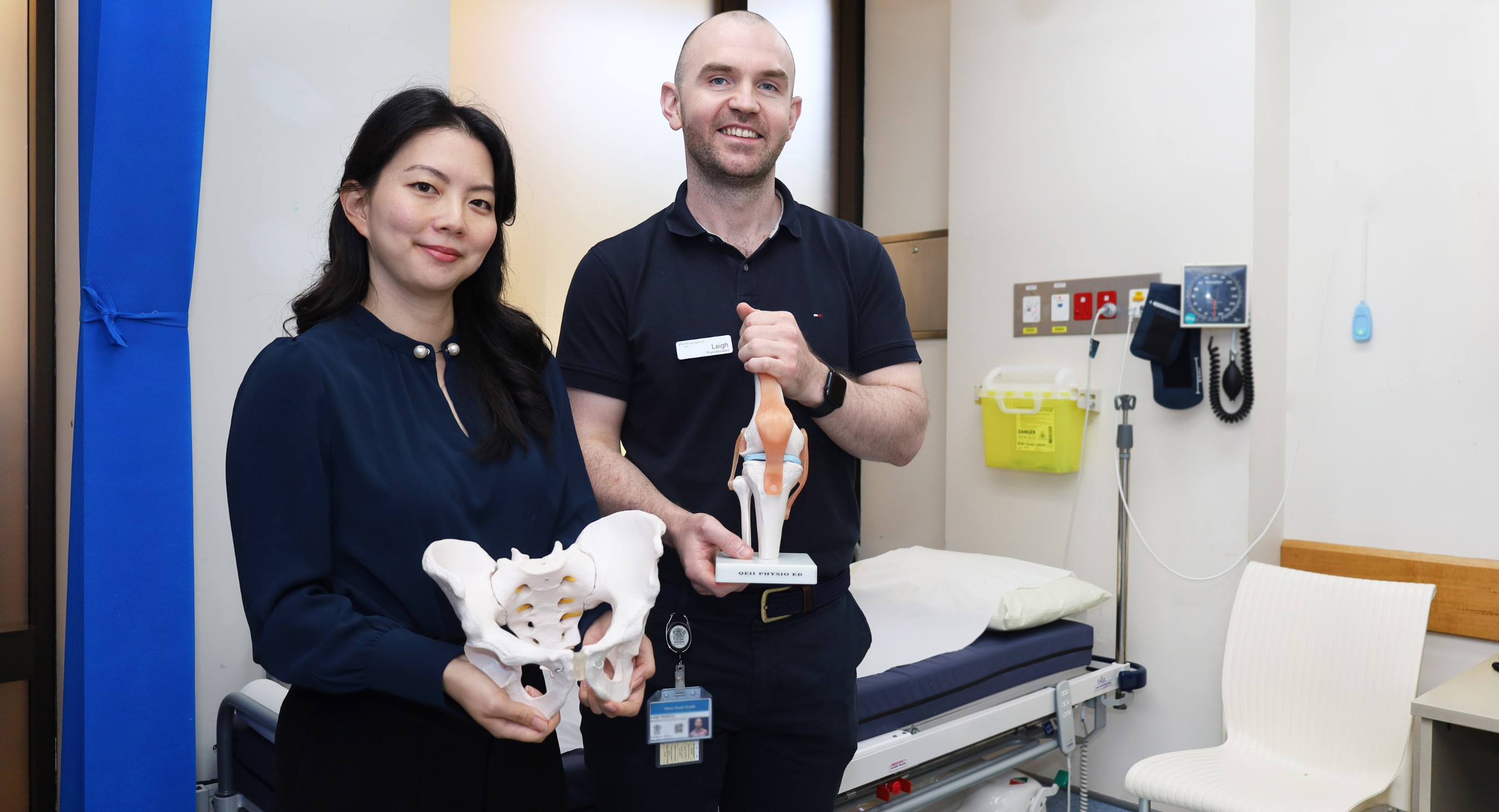 Female doctor and male physiotherapist in clinical room, holding 