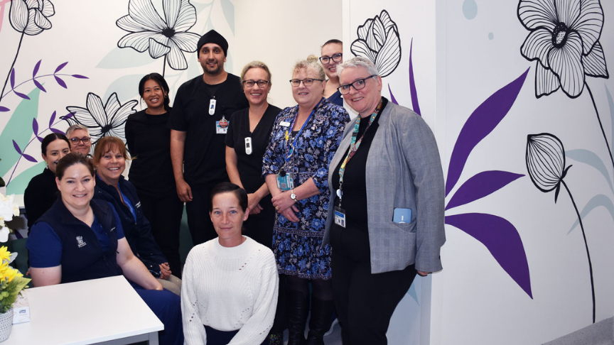 Mixed gender group of people standing in front of a wall with a floral mural