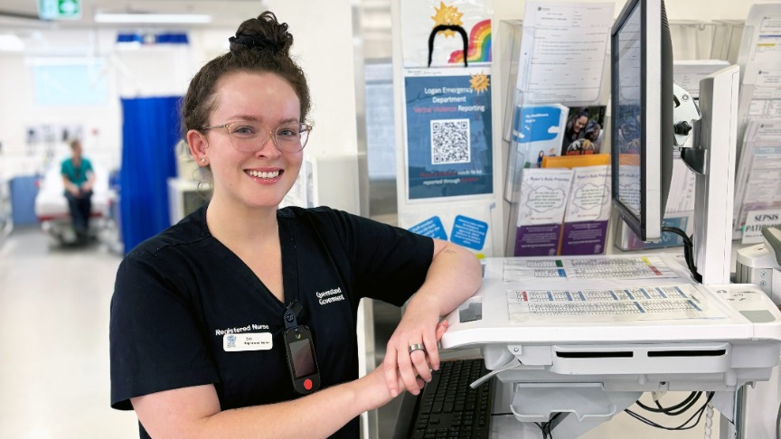 Female nurse standing resting against a computer in a clinical area