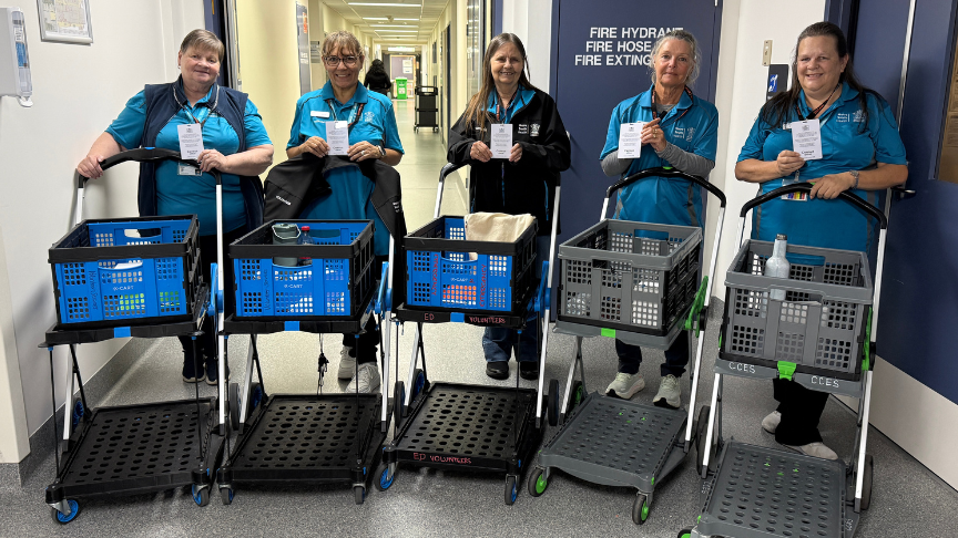 Small group of women in blue polo shirts behind trolleys