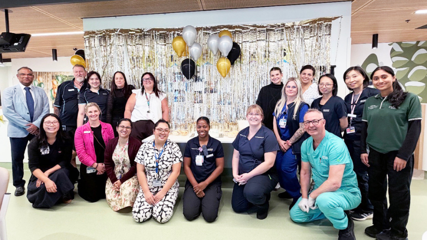 Large group of workers in front of a silver tinsel backdrop 