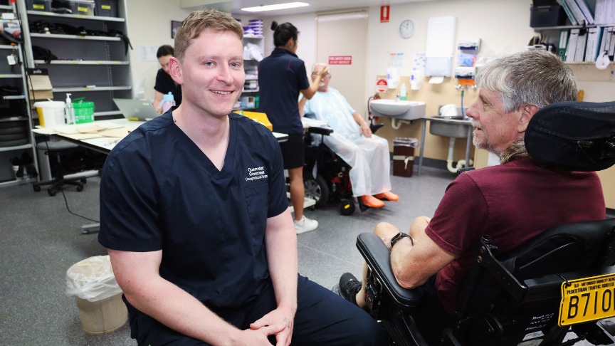 Male health worker and patient facing each other in a rehab gym.