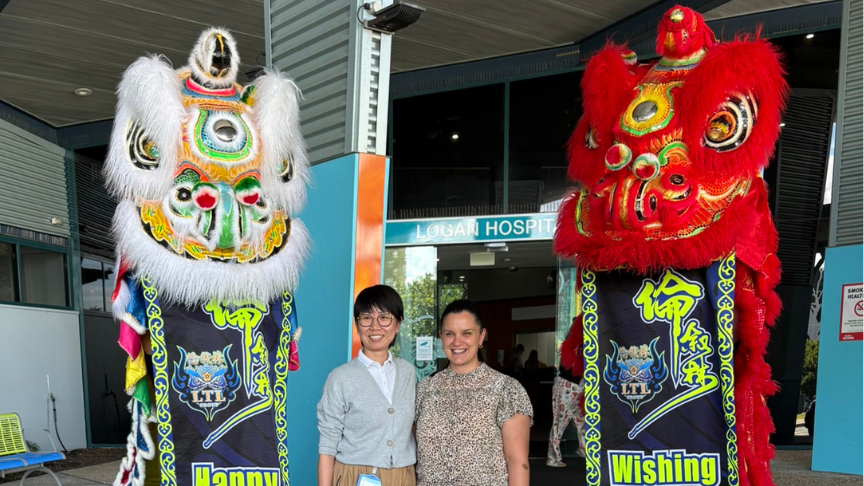 Two hospital workers in plain-clothes standing in between two Chinese Dragon performers
