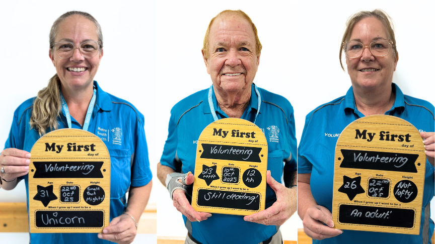 Three Volunteers each holding a wooden board in front of a white background