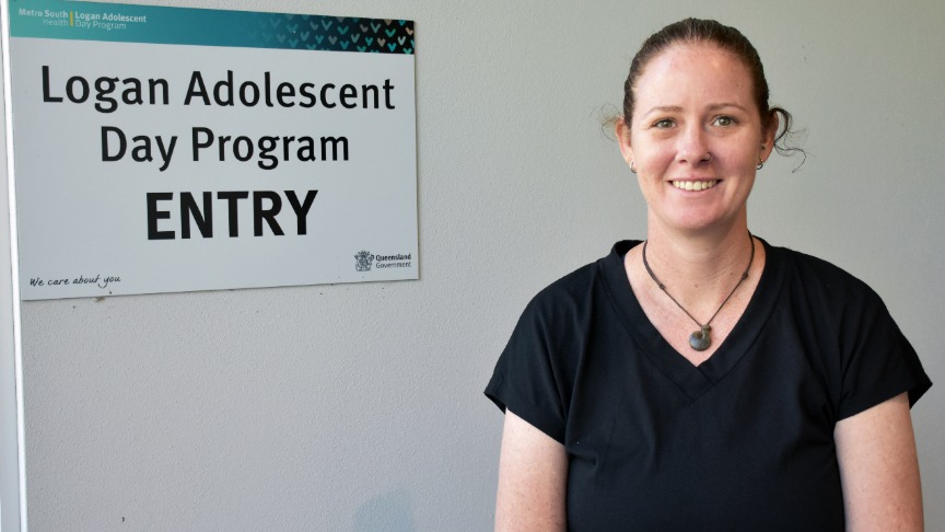 a lady in a black shirt standing in front of a grey wall