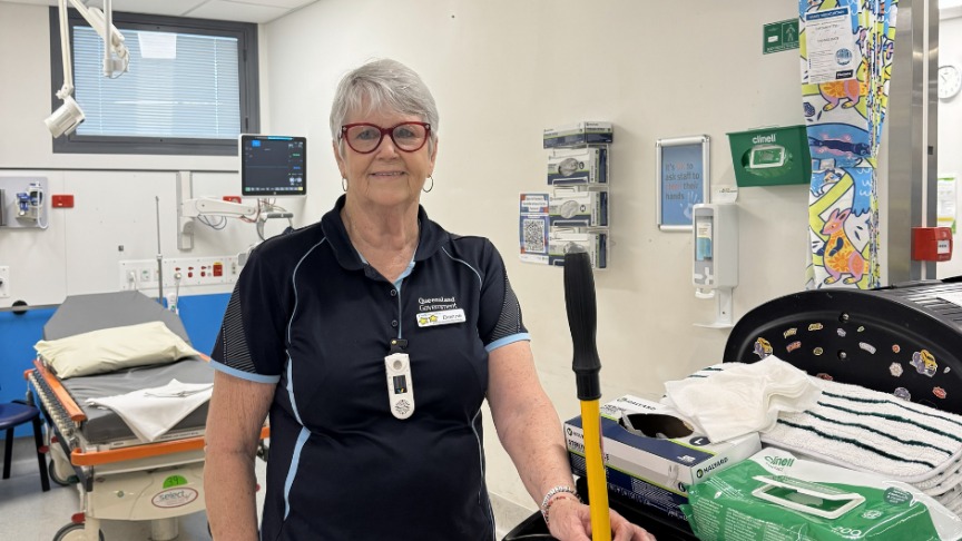 A female standing with cleaning equipment in a clinical setting 