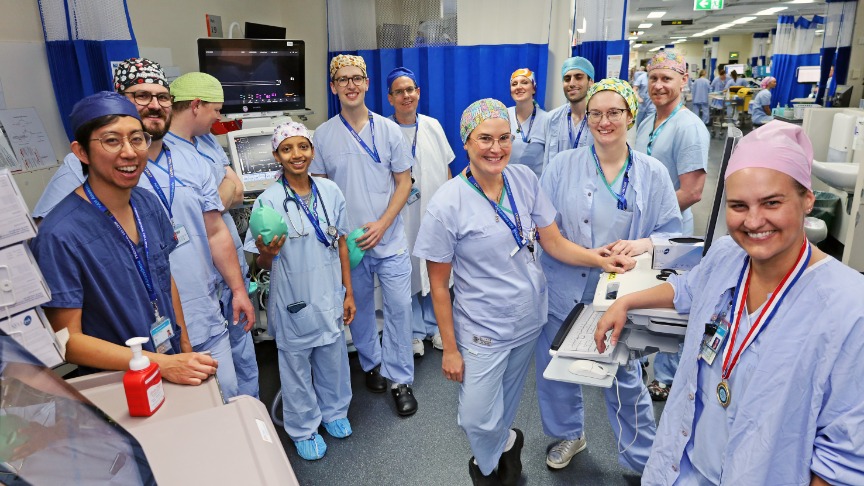 A group of anaesthetists in scrubs poses together for a photo in a clinical area of the hospital