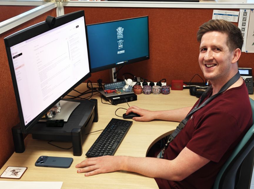 Doctor wearing scrubs sitting at a computer in an office space