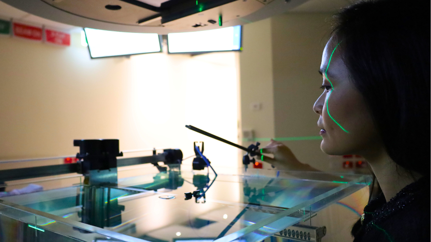 Medical Physicist Lucy Sim stands in a TrueBeam Linear Accelerator to calibrate