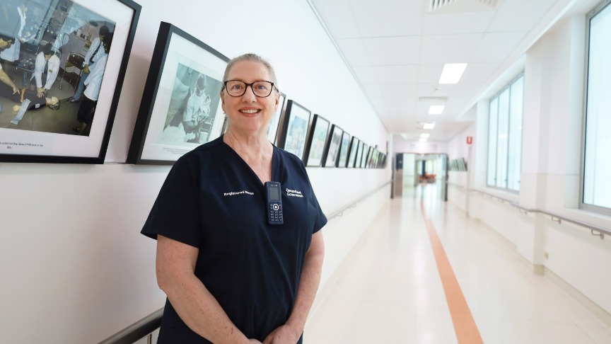 Nurse standing in hallway lined with framed photos