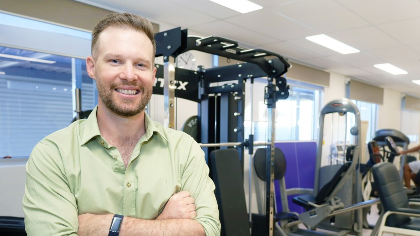 Male physio standing in gym with arms crossed