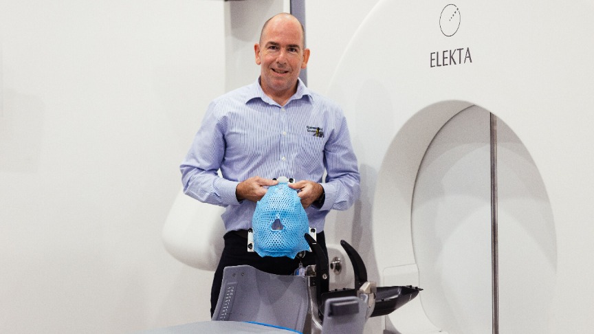 A man named Michael Jenkins is positioned next to the Gamma Knife MRI machine in a medical environment