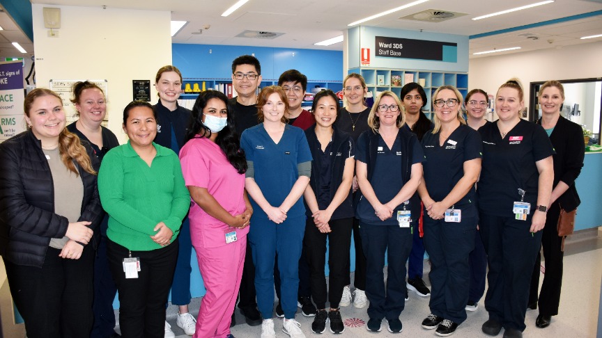large team of healthcare professionals standing in a hospital ward setting