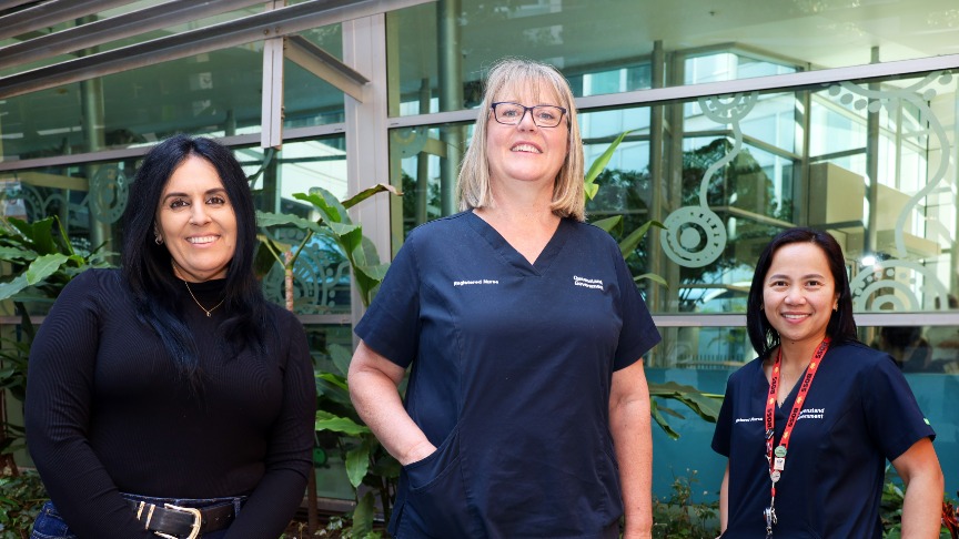 Three female health workers stand in PAH Atrium.