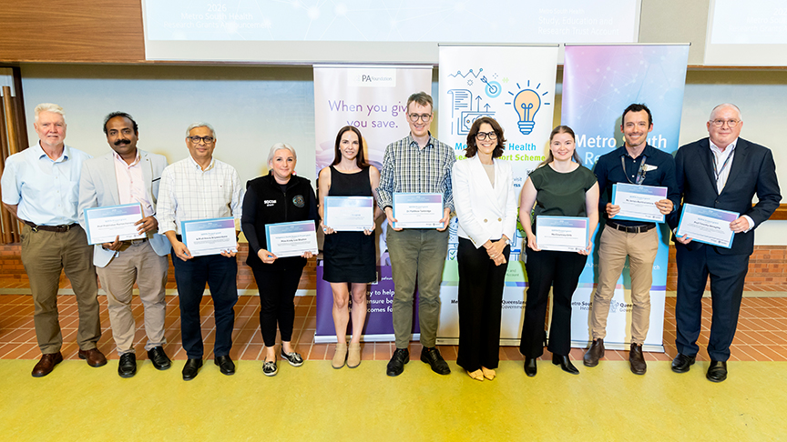 A row of researchers holding certificates in an auditorium