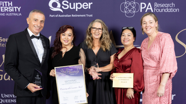 5 people in formal wear holding awards in front of a purple background