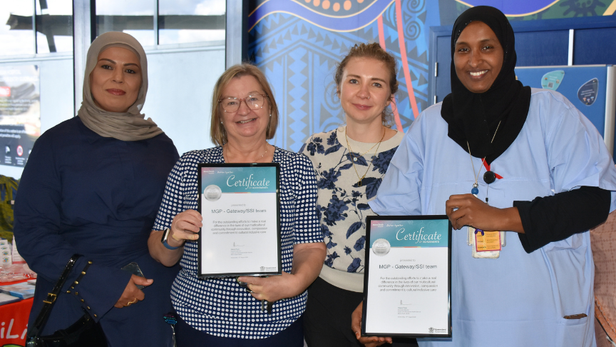 Group of four multicultural staff holding a framed certificate