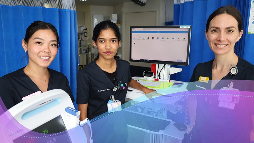 Three nurses standing in ward room with a computer to the left.