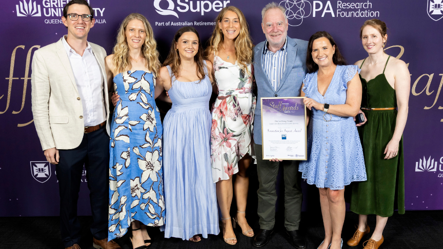 Group of people in formal wear holding a framed certificate