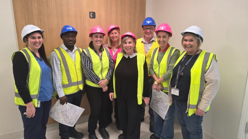 group of workers wearing high vis vests and hard hats standing in front of a plain coloured wall
