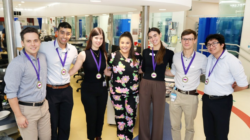 6 medical students wearing gold medals pose with ED doctor in QEII ED