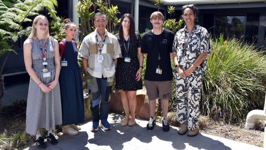 Group of mixed gender standing outside in front of a garden