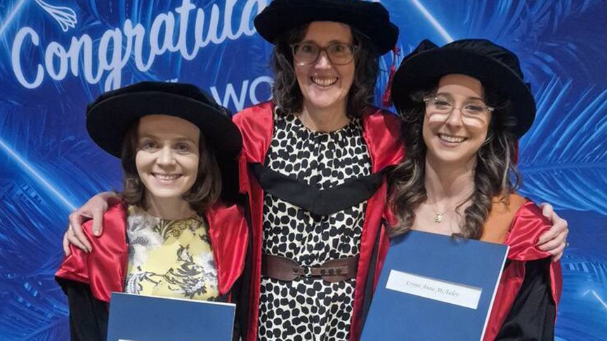 Three women wearing mortarboards at a graduation ceremony
