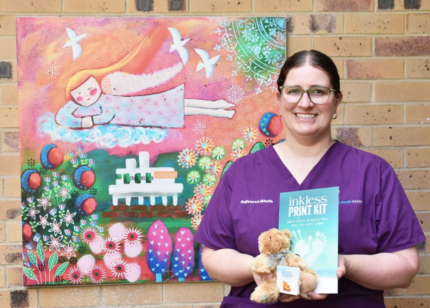 Midwife in purple scrubs holding a teddy