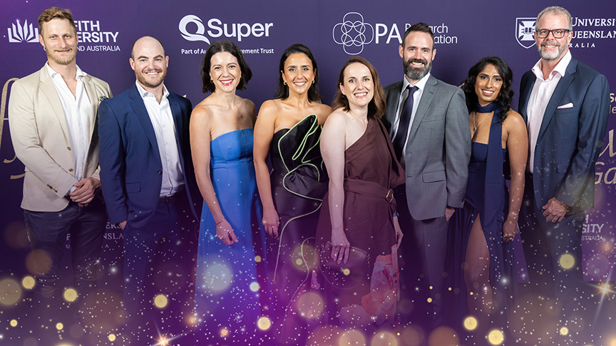 A group of people in formal attire standing in front of a backdrop at the Metro South Health Staff Awards 2024 in Brisbane.