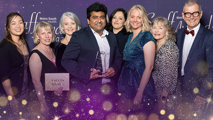 A group of people in formal attire standing in front of a backdrop at the Metro South Health Staff Awards 2024 in Brisbane.