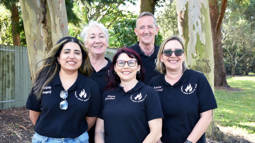 a group of nurses in black polo shirts standing in a park