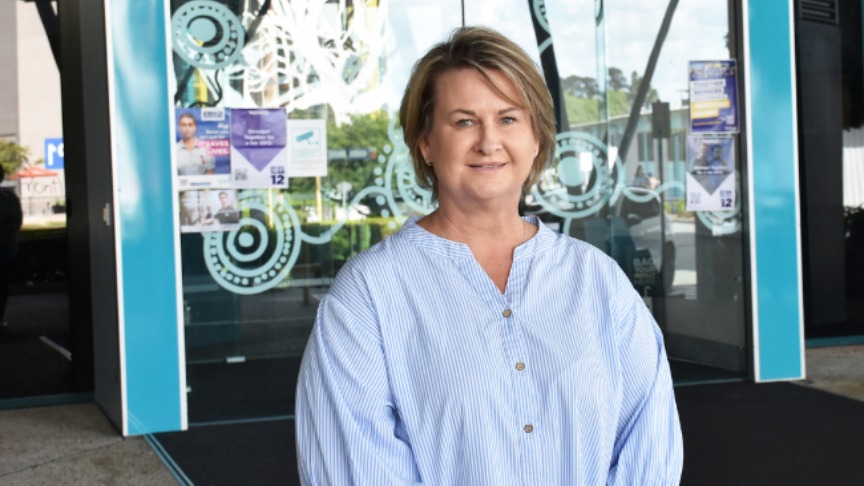 Woman in a blue and white striped shirt standing at the entrance to Logan Hospital