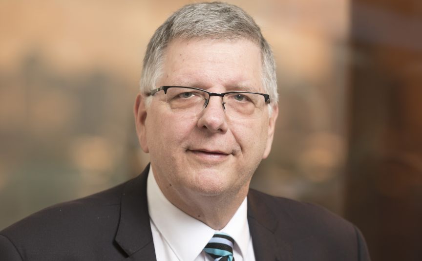 A portrait of an experienced male professor wearing glasses and a striped tie