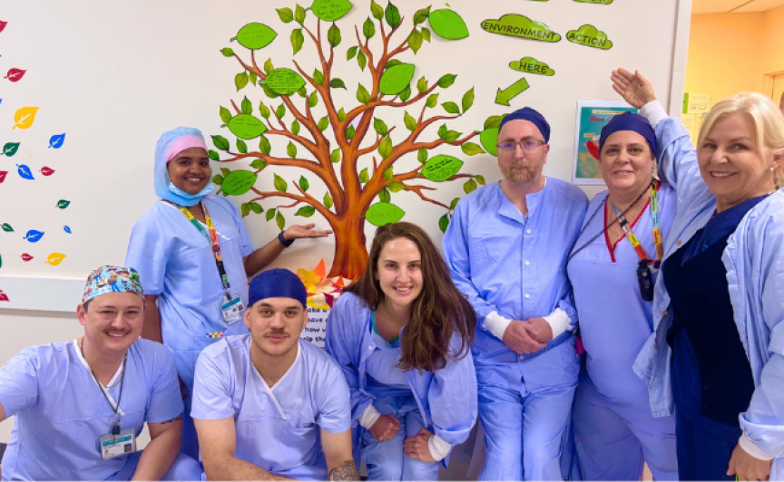 a group of people in blue theatre scrubs in front of a paper tree project
