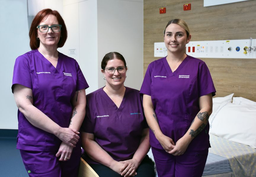 Three midwives in purple scrubs in a clinical splace