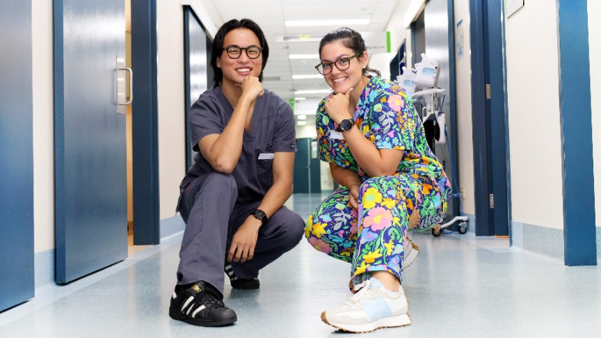 Two dermatologists, Dr. Ed and Dr. Kat, posing in scrubs in a hallway at PA Hospital's dermatology clinic