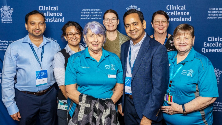 seven people standing in from of a blue background at a conference