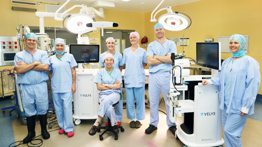 Surgical team posing in operating theatre with VELYS surgical robot