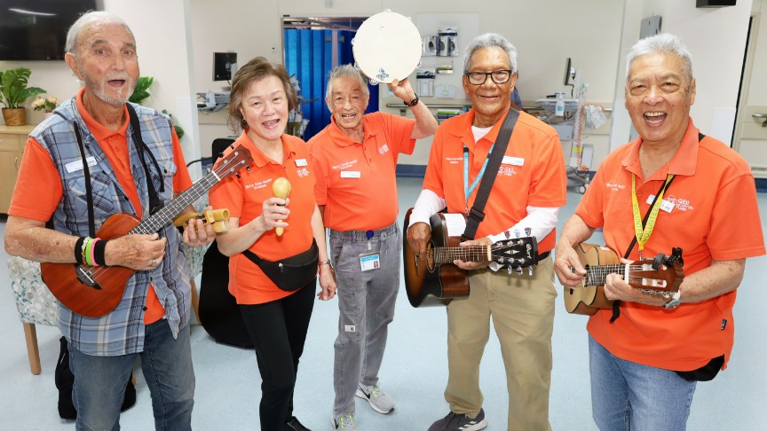 Five volunteers hold various instruments in a hospital ward