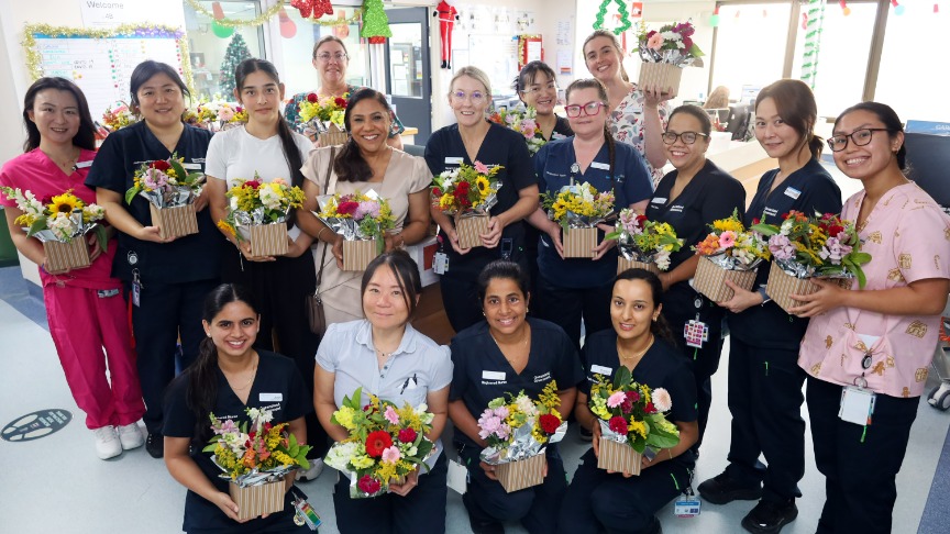 Nursing team holding bouquets of flowers on hospital ward